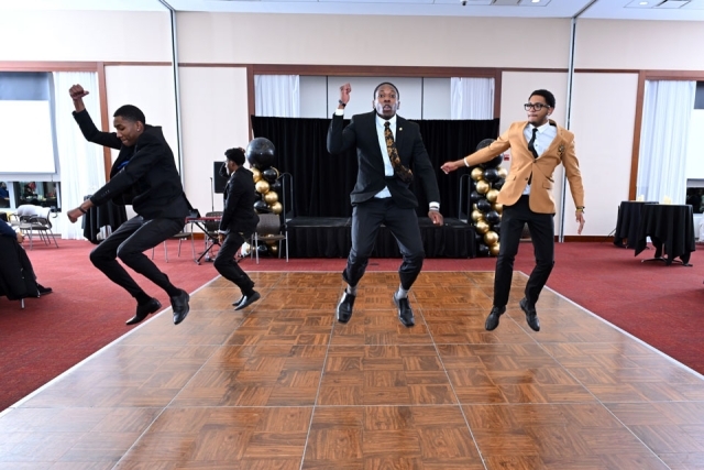 Student performers mid-jump during a high-energy dance performance at the Martin Luther King Jr. Legacy Dinner.