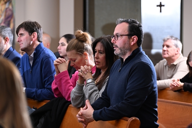 Couples sitting in a church kneeling in prayer 