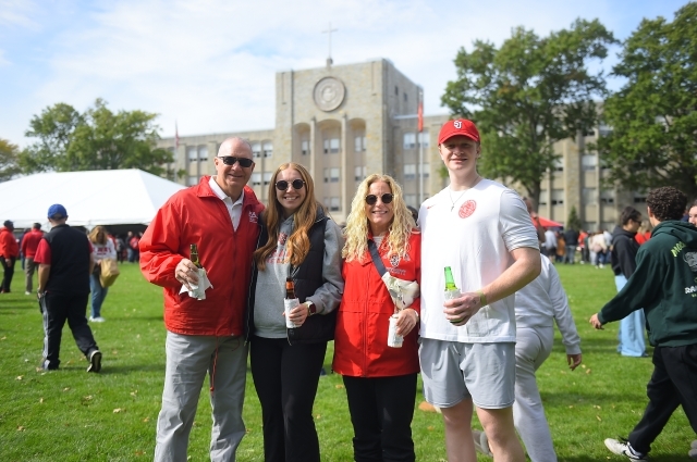 Four people on the Great Lawn with St. Augustine Hall in the background