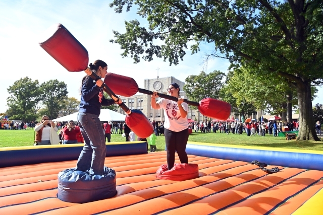 Two people jousting on a large inflatable.