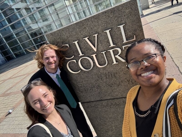 Three St. John’s Law CLARO volunteers outside the Queens Civil Courthouse.