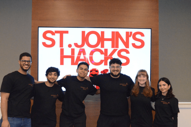 Students standing behind a sign with the words "St. John's Hacks" 