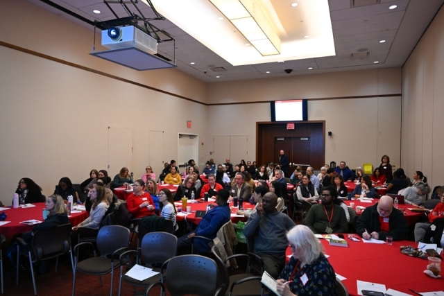 Room of working professionals listening at an event 