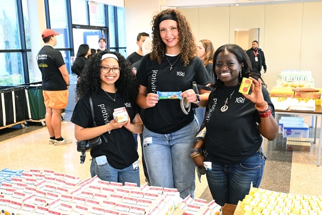 Three woman holding up pantry food items 
