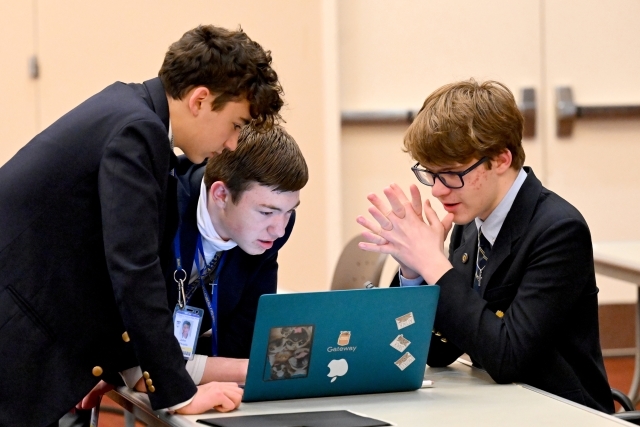 Three young men looking at a computer