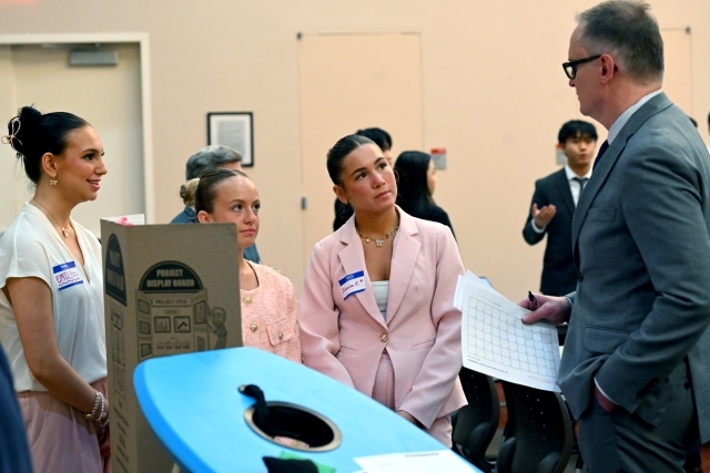 Group of female students speaking to a professor