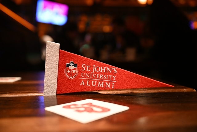 St. John’s University alumni pennant displayed on a bar counter with a blurred background