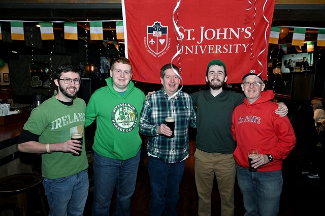 St. John’s University alumni standing together with drinks during a St. Patrick’s Day gathering
