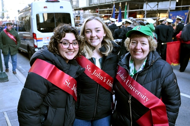 Large group of St. John’s University students and alumni posing together with a banner on a New York City street