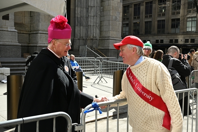 St. John’s University alumnus greeting a member of the clergy during a St. Patrick’s Day parade
