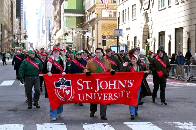 St. John’s University alumni and students marching with a red banner in a New York City St. Patrick’s Day parade