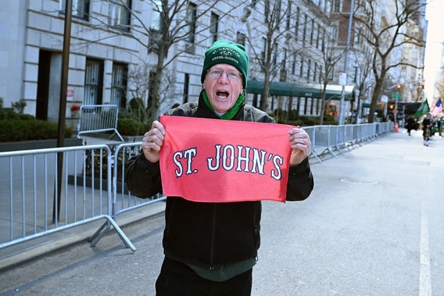 St. John’s University alumnus holding a red banner and cheering during a St. Patrick’s Day parade
