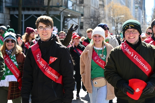 Group of St. John’s University students and alumni walking together during a St. Patrick’s Day parade in New York City