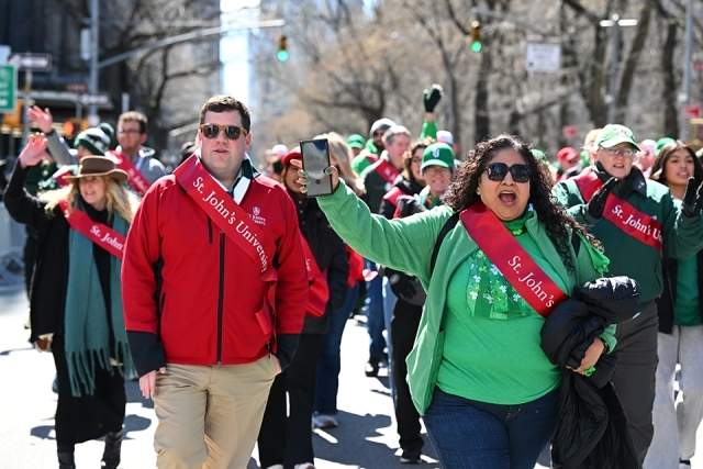 St. John’s University alumni cheering and walking together during a St. Patrick’s Day parade