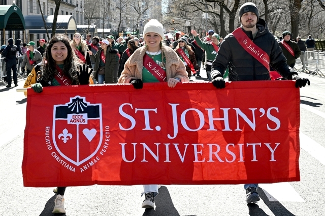 St. John’s University students holding a red banner while walking in a St. Patrick’s Day parade