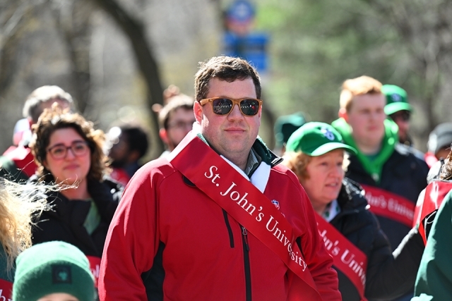 St. John’s University alumnus wearing a red jacket and sash during a St. Patrick’s Day parade