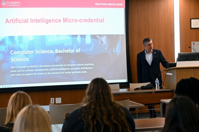 Man speaking in front of a projector screen 