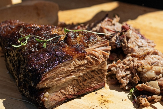 Close-up of sliced smoked brisket showing a crispy exterior and tender interior on a cutting board.