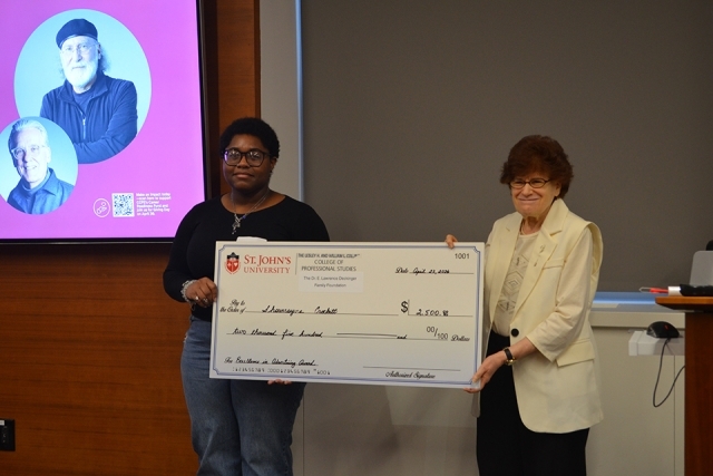 Two people holding a award check 