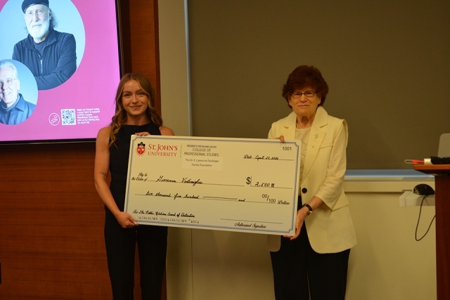 Two people holding a award check 