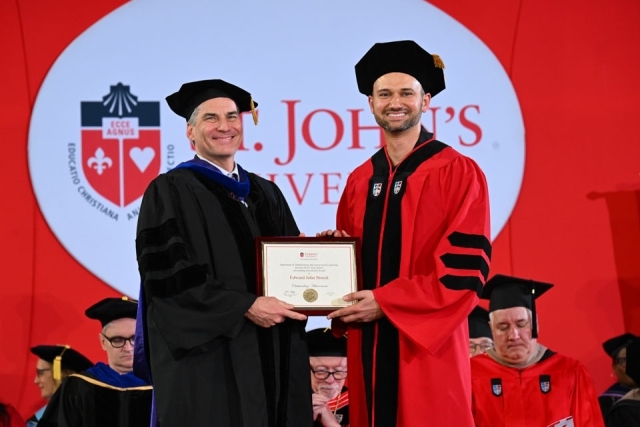St. John’s University graduate receives an academic award on stage during commencement ceremony.