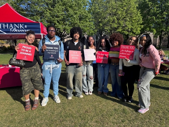 students standing with signs thanking their donors
