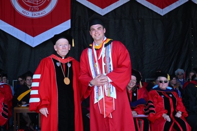 Religious leader speaks at the podium during St. John’s University commencement ceremony outdoors.