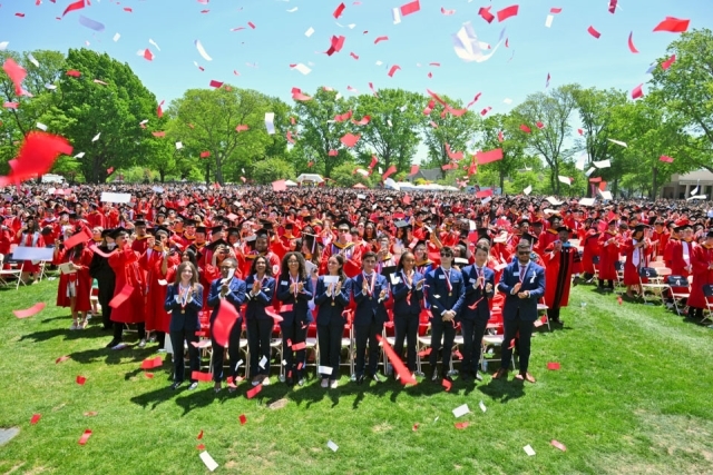Graduates celebrate as confetti falls over the crowd during St. John’s University commencement ceremony on the Great Lawn.