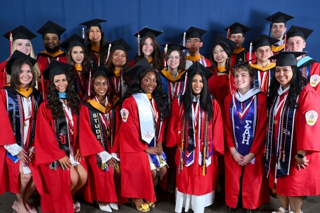 Group of St. John’s University graduates pose together in caps and gowns before commencement ceremony.