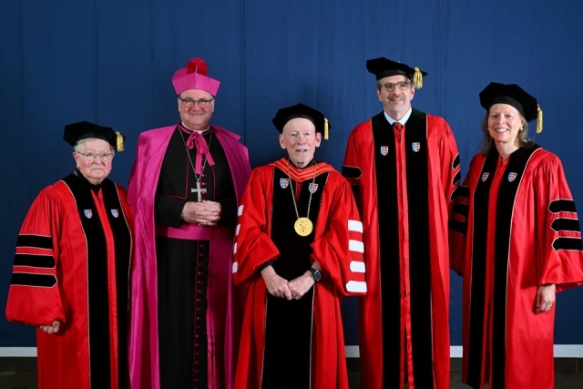 Group of St. John’s University graduates pose together in caps and gowns before commencement ceremony.