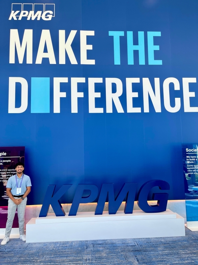 Student photo in front of a sign that says "Make The Difference"