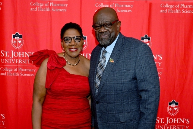 Two gala attendees pose in front of a St. John's University College of Pharmacy and Health Sciences backdrop.