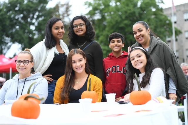 Group shot of 7 student and family members painting pumpkins