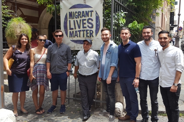 Group of students standing in front of Immigrant Lives Matter sign