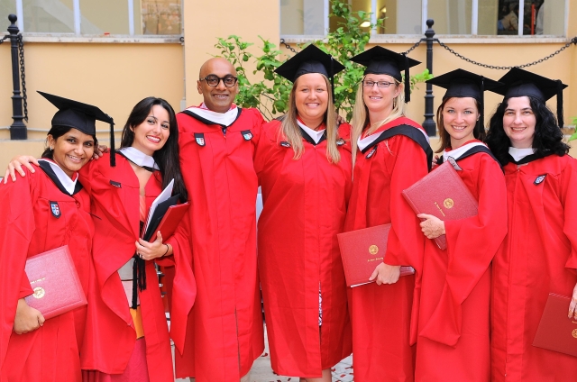 Seven students in caps and gowns posing for photo