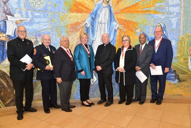 University community members in front of the mural wall at St. Thomas More Church