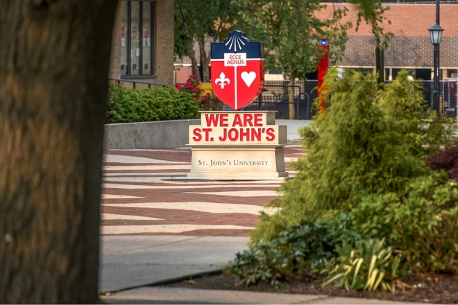 We Are St. John's crest statue outdoors on Queens Campus