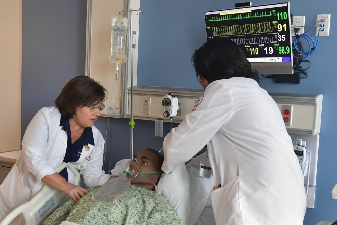 College of Pharmacy and Health Sciences students helping simulation patient in bed