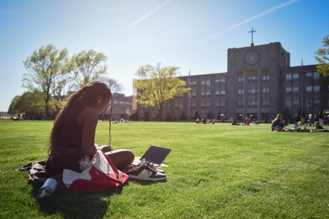 St. John's student sitting on great lawn infront of St. Augustine