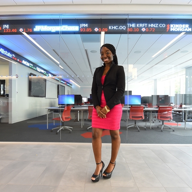 Graduate Student Standing in front of Tobin Stock Ticker 