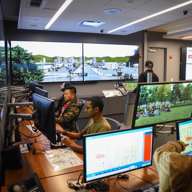 Students working at computers and in front of a large cybersecurity screen 