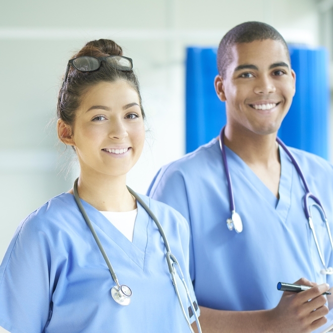 Two nursing students posing for photo in scrubs