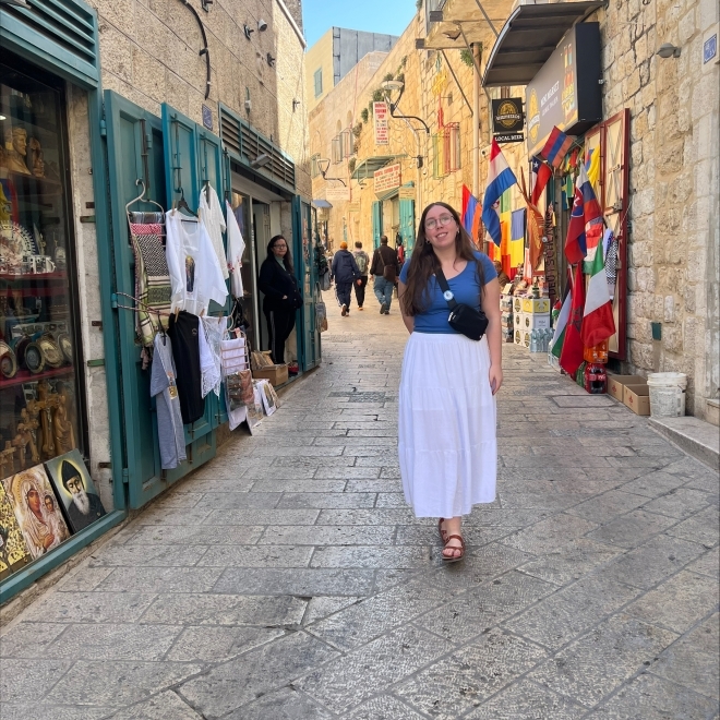 Girl in blue shirt and white long shirt standing in the middle of a street in Italy 