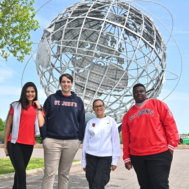 Male and female students standing in front of the Queen's Unisphere 