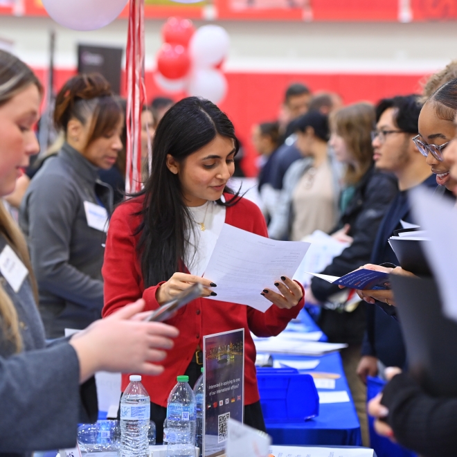 Intern recruiter looking at a students resume at a career fair 