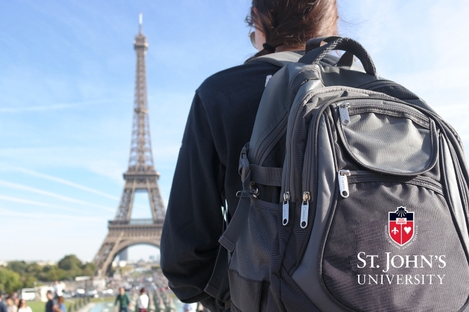 Student wearing St. John's University backpack infront of Eiffel tower