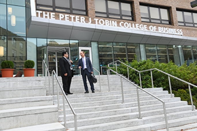 Two males walking down the stairs in front of Tobin