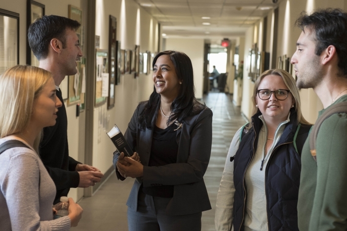 faculty speaking with 4 students in the hallway