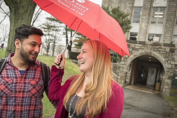 Two students walking in the rain with umbrella