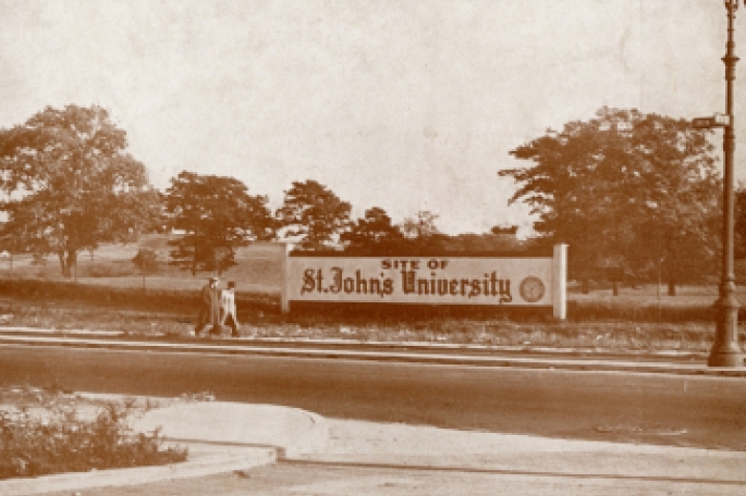 Site of St. John's University Sign with 2 people walking past it
